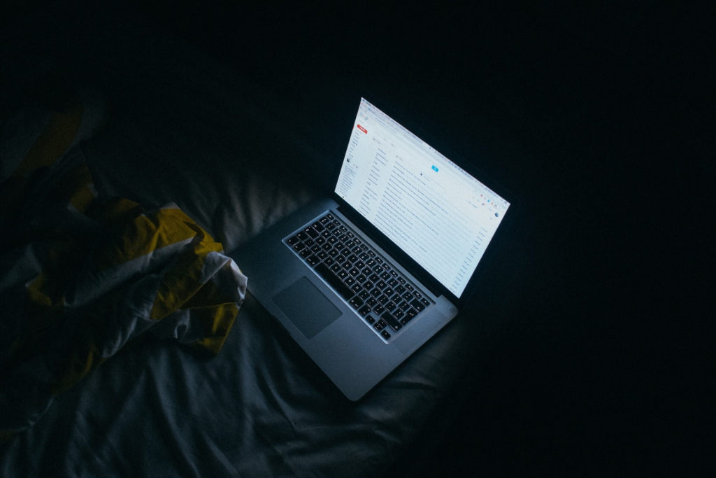 a laptop in a dark room emitting artificial blue light