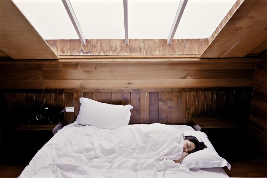 a woman sleeping with light shining on her from a skylight
